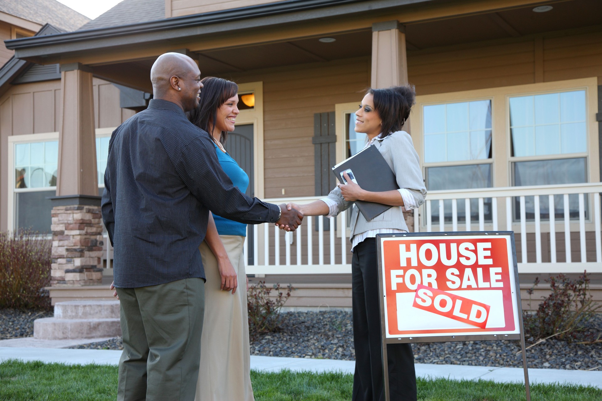 Couple shakes hands with Real Estate Agent outside new house