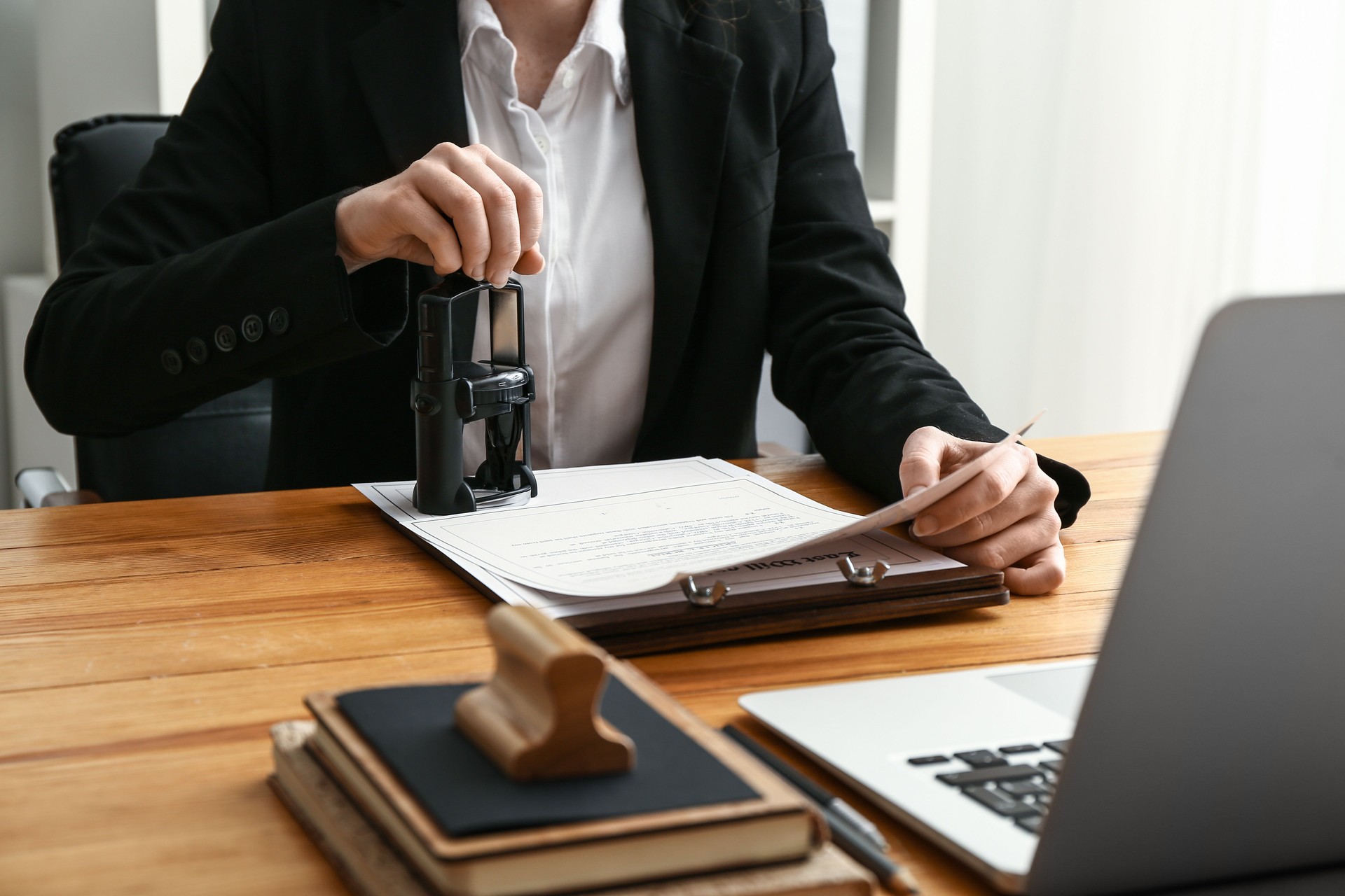 Person stamping an official document with an automatic stamp at a desk